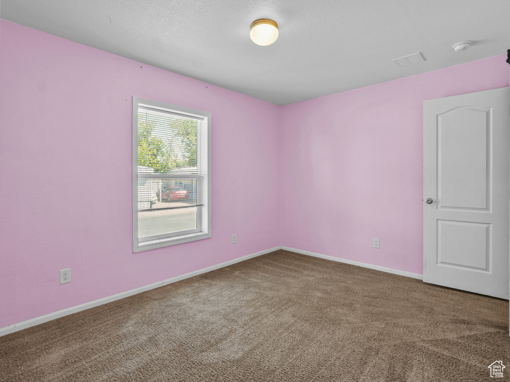 Carpeted spare room with a smoke detector and baseboards
