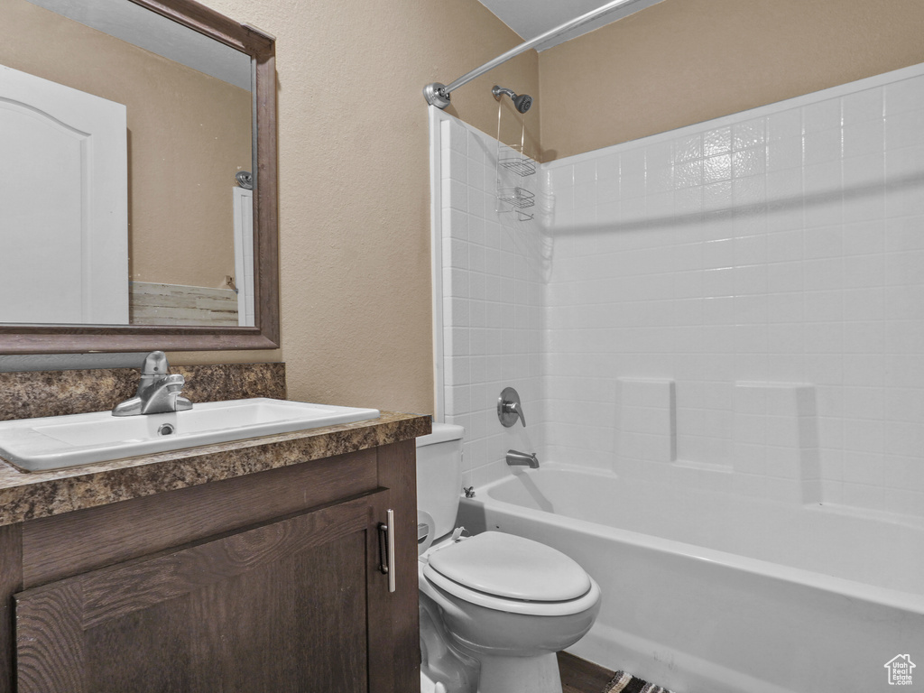 Bathroom with toilet, vanity, shower / bath combination, and a textured wall