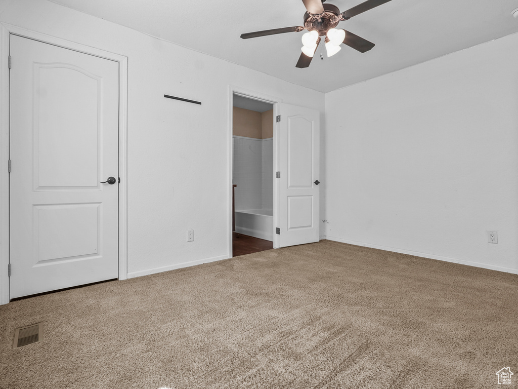Unfurnished bedroom featuring carpet flooring, baseboards, ensuite bath, and a ceiling fan