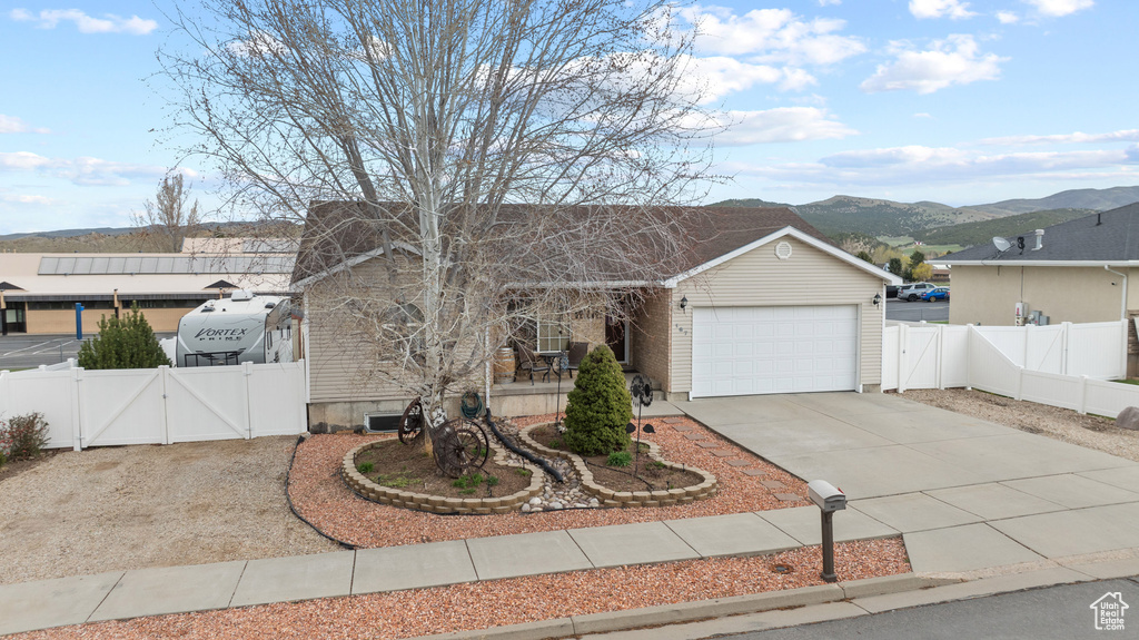 View of front of property with a garage, a gate, a mountain view, driveway, and fence