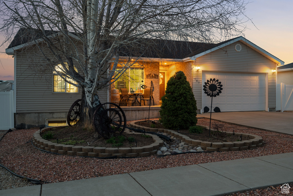 Single story home with driveway, fence, covered porch, and a garage