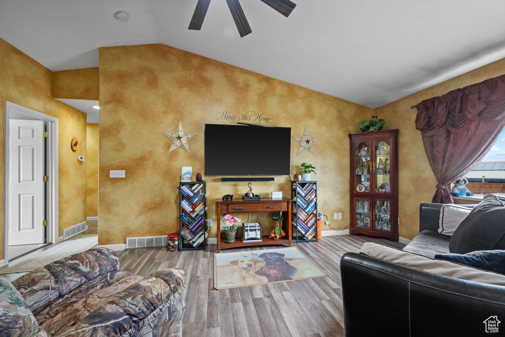 Living area with lofted ceiling, wood finished floors, visible vents, and ceiling fan