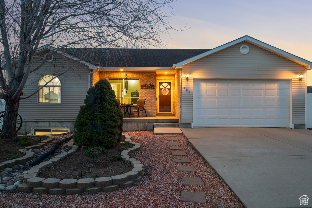 Single story home featuring concrete driveway, a garage, covered porch, and a shingled roof
