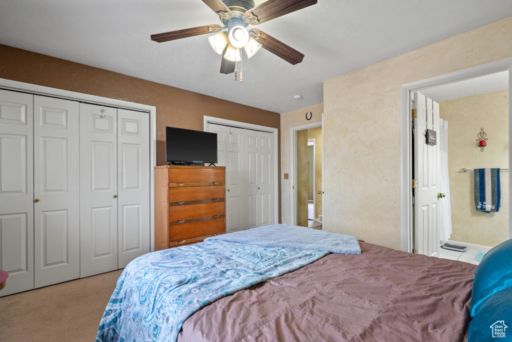 Bedroom with a ceiling fan, multiple closets, and carpet floors