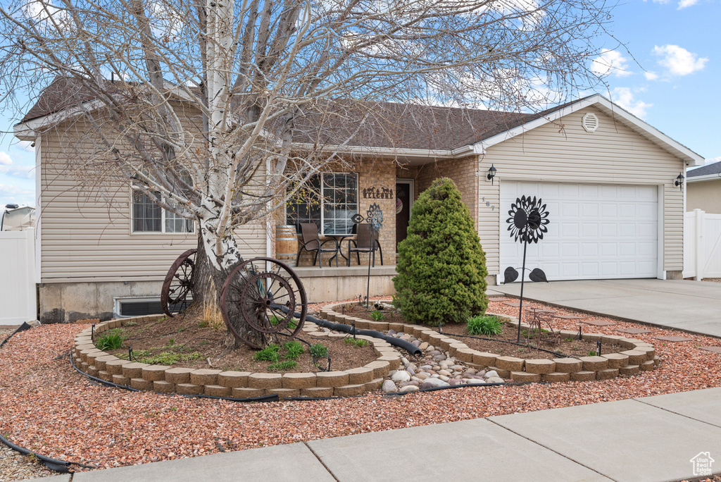 View of front of house with concrete driveway, covered porch, an attached garage, fence, and brick siding