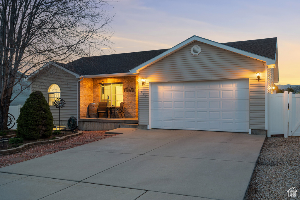 Single story home with driveway, fence, a shingled roof, and a garage