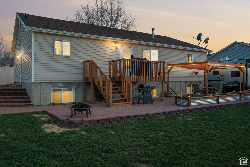 Rear view of house featuring a yard, stairway, a fire pit, a wooden deck, and a patio area