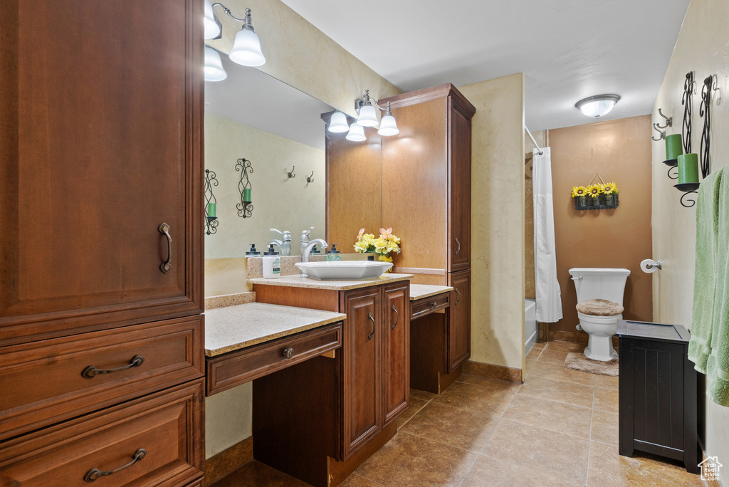 Bathroom featuring baseboards, shower / bath combo with shower curtain, toilet, vanity, and tile patterned flooring