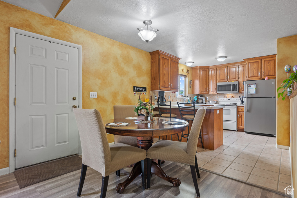 Dining area with a textured ceiling, light wood-style floors, and baseboards