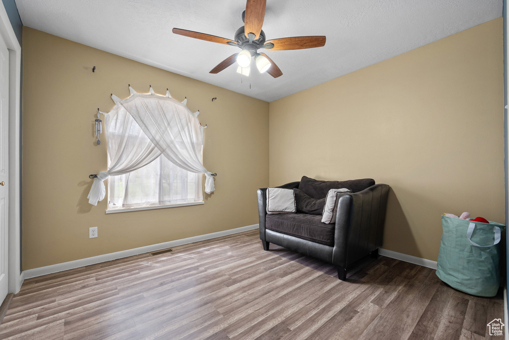Sitting room with ceiling fan, wood finished floors, and baseboards
