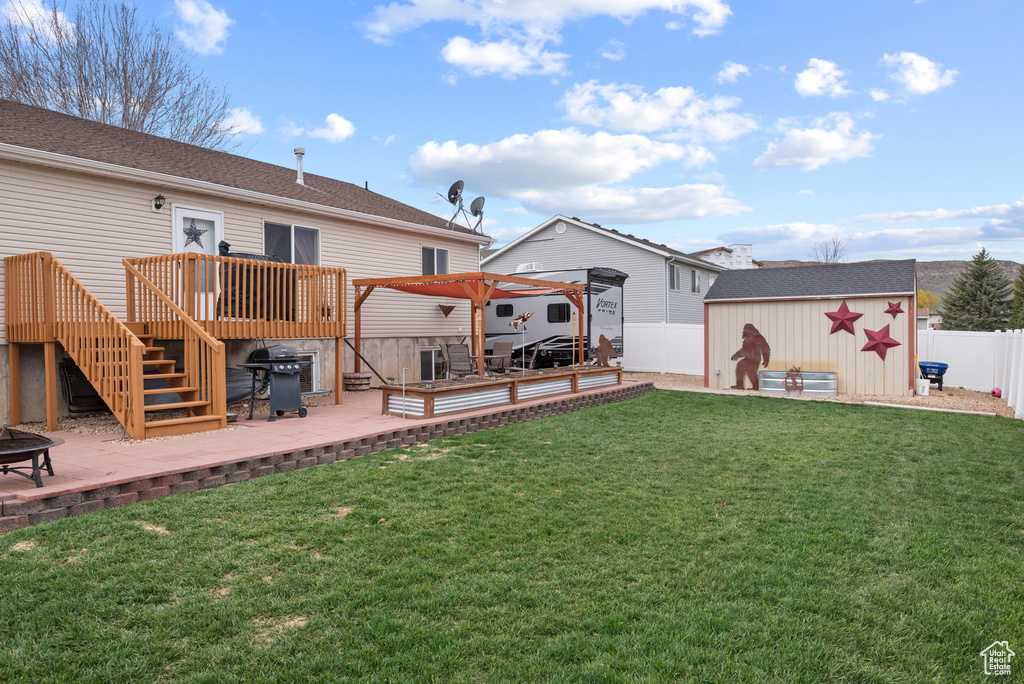 Back of property with an outdoor structure, a yard, a wooden deck, and a fenced backyard
