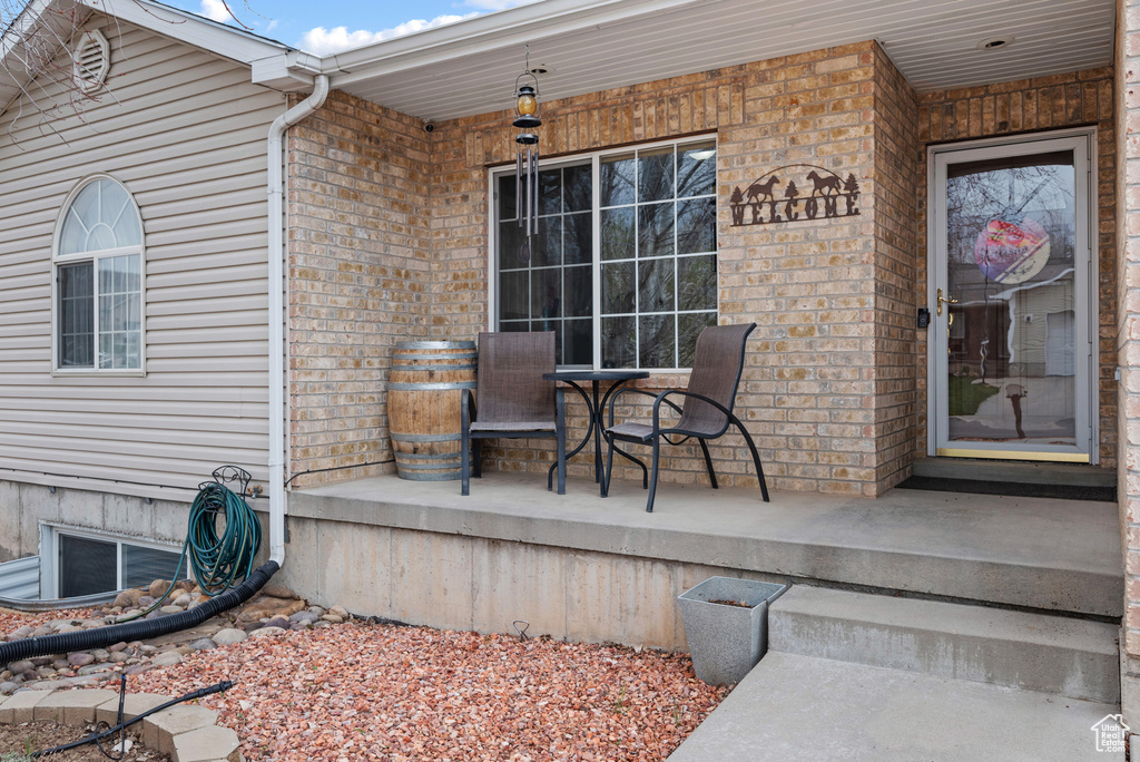 Entrance to property with covered porch and brick siding