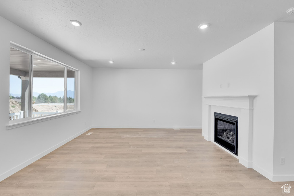 Unfurnished living room with a fireplace, recessed lighting, and light wood-type flooring