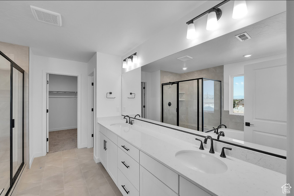 Bathroom featuring a shower stall, a walk in closet, double vanity, a bathtub, and tile patterned floors