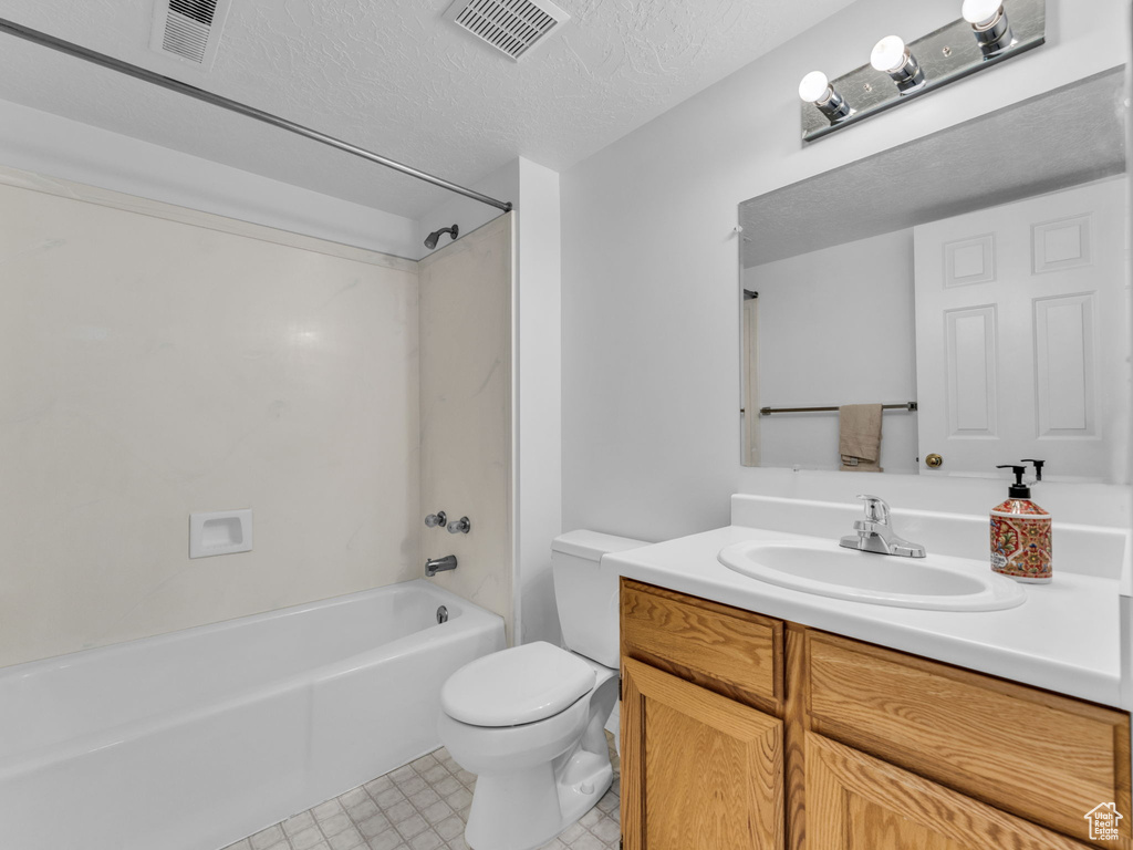Bathroom featuring vanity, toilet, bathtub / shower combination, and a textured ceiling