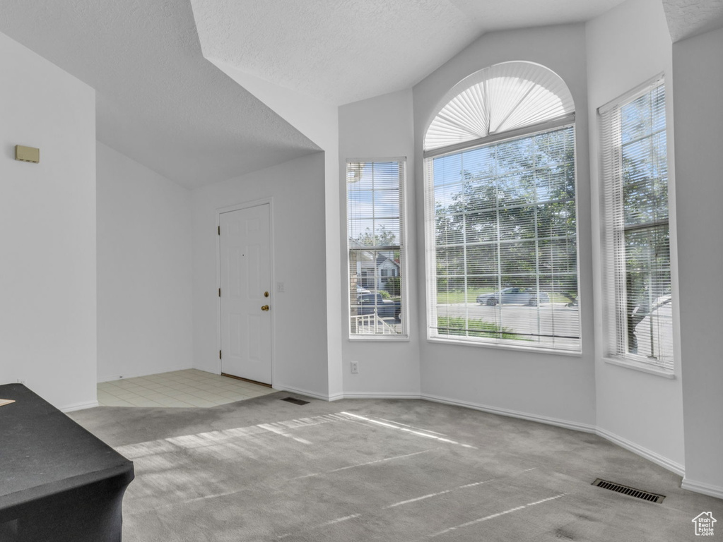 Foyer entrance with vaulted ceiling, carpet flooring, a textured ceiling, stairway, and baseboards