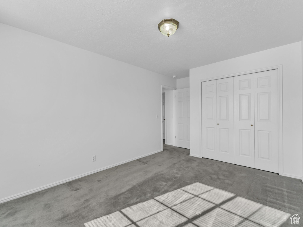 Unfurnished bedroom featuring carpet flooring, baseboards, and a closet