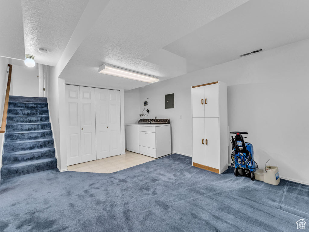 Finished basement featuring electric panel, washing machine and dryer, a textured ceiling, light colored carpet, and stairway