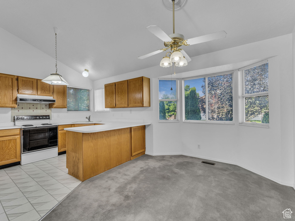 Kitchen with white electric range oven, under cabinet range hood, light countertops, a peninsula, and lofted ceiling