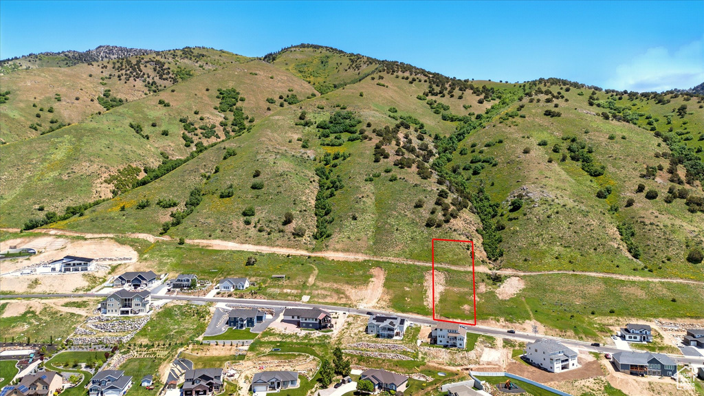 Aerial overview of property\'s location featuring property parcel outlined, nearby suburban area, and a mountainous background