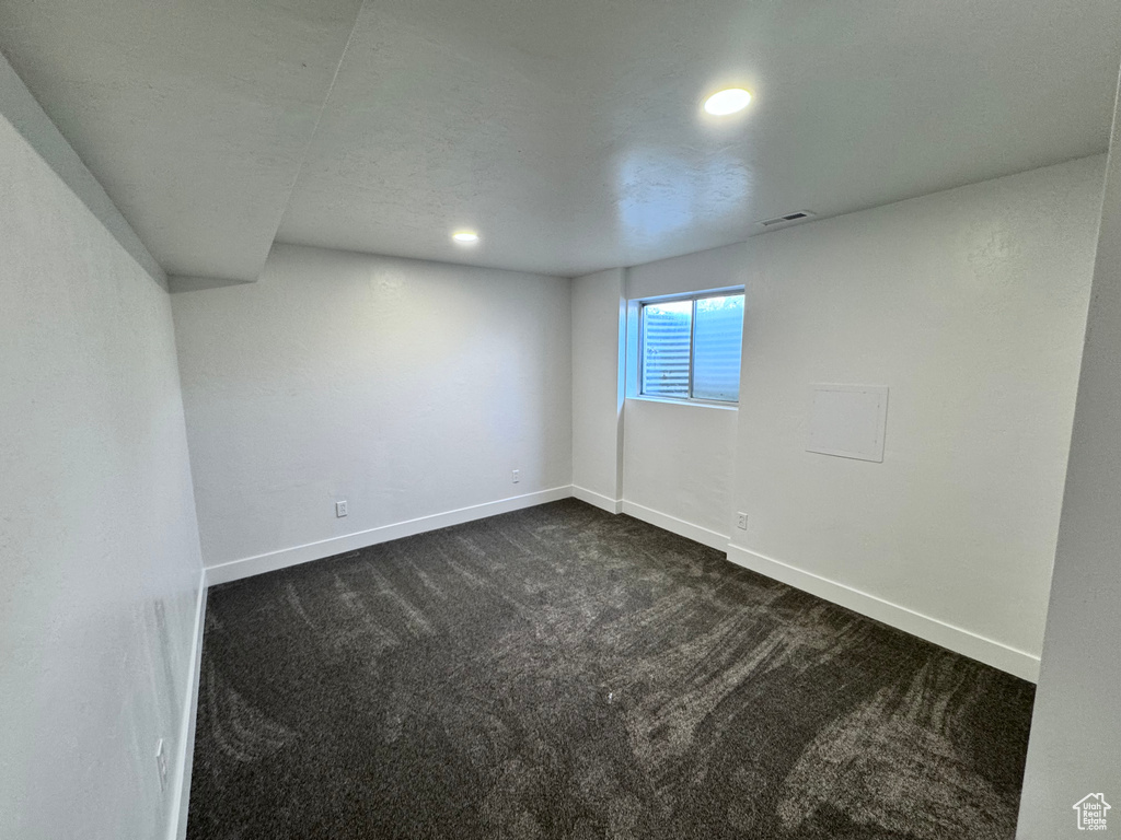 Empty room featuring dark colored carpet, baseboards, and recessed lighting