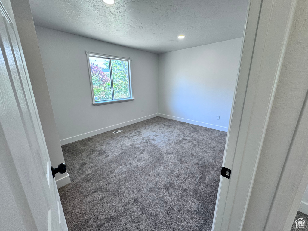 Empty room with carpet floors, baseboards, recessed lighting, and a textured ceiling