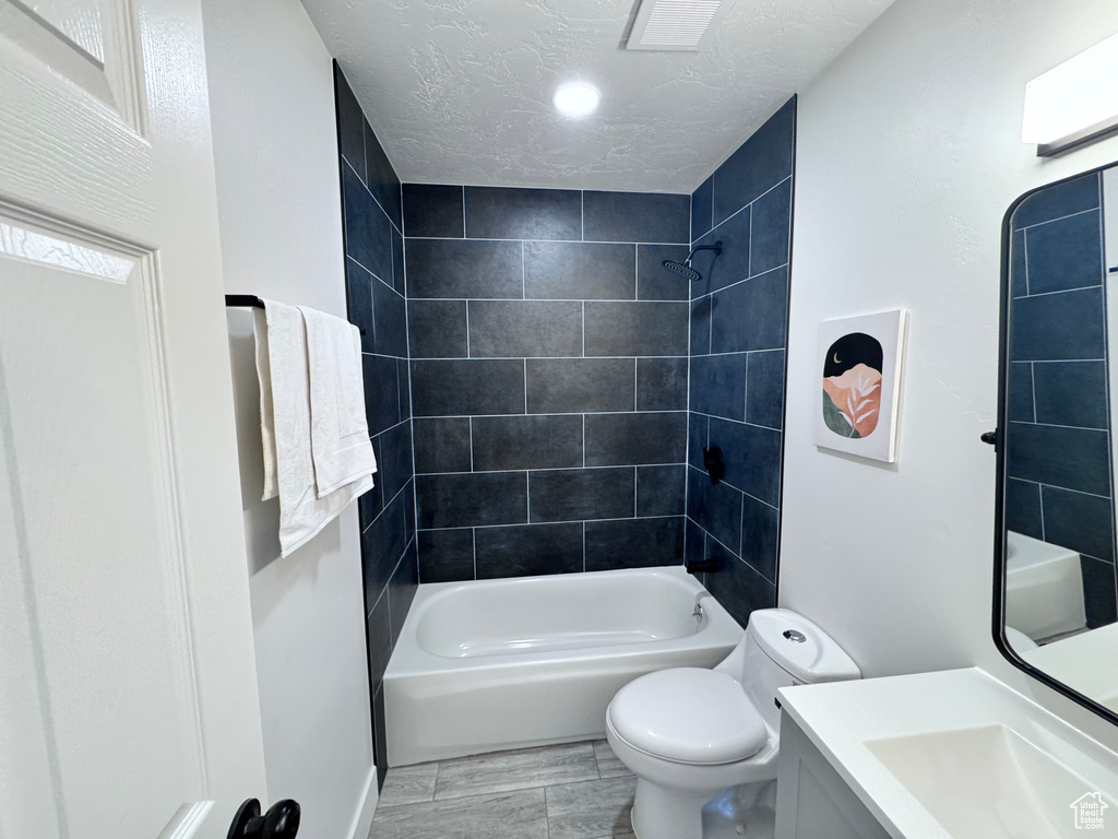 Full bathroom featuring toilet, vanity, shower / bath combination, and a textured ceiling