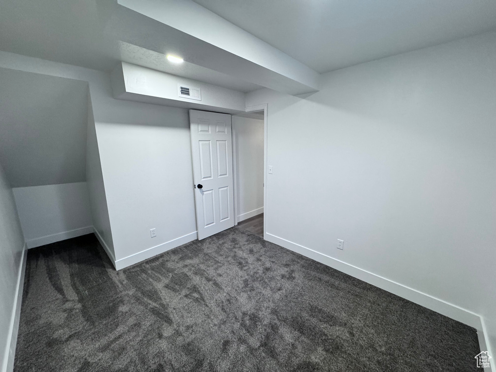 Bonus room with baseboards and dark colored carpet