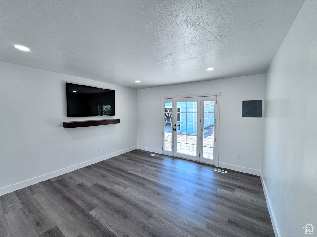 Unfurnished living room featuring electric panel, dark wood-style flooring, baseboards, recessed lighting, and a textured ceiling
