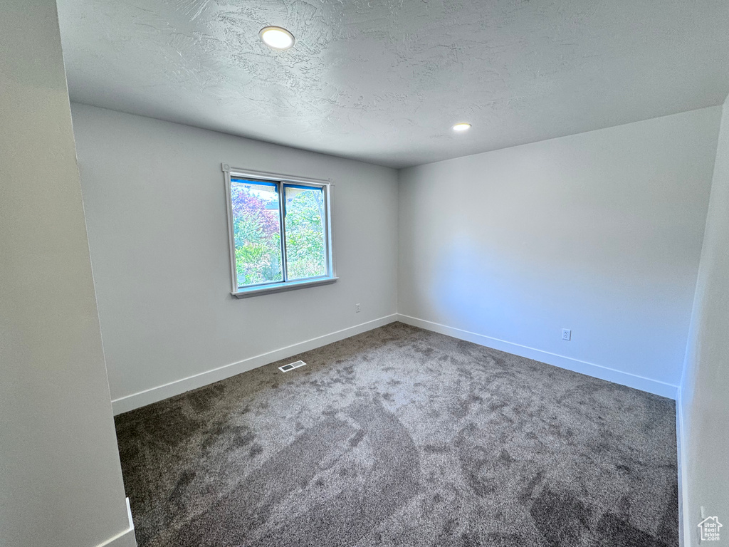 Spare room featuring carpet floors, baseboards, recessed lighting, and a textured ceiling