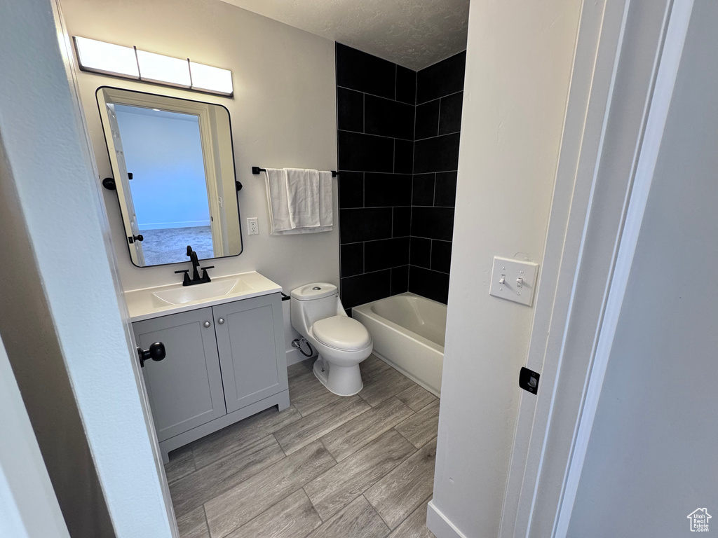 Bathroom featuring vanity, toilet, bathing tub / shower combination, and wood finished floors