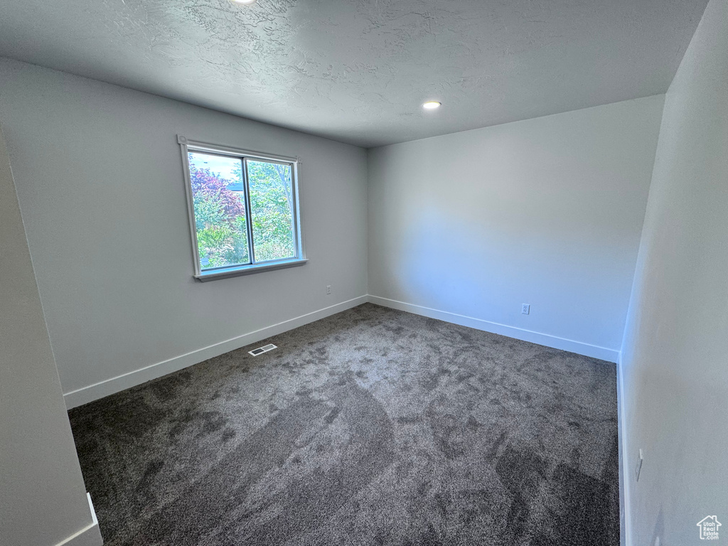 Carpeted spare room with baseboards, a textured ceiling, and recessed lighting