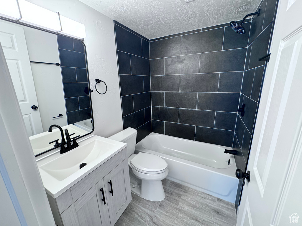 Full bathroom with a textured ceiling, vanity, toilet, and bathing tub / shower combination