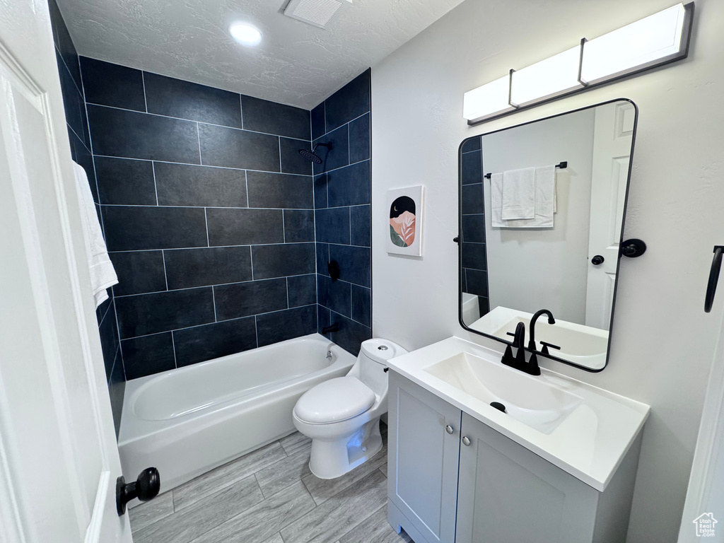Bathroom with toilet, vanity, shower / bathtub combination, a textured ceiling, and wood finished floors