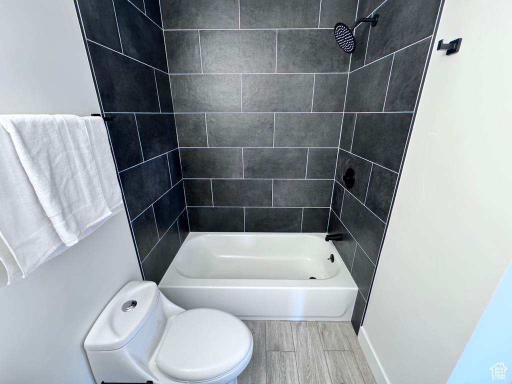 Bathroom featuring toilet, wood finish floors, and bathing tub / shower combination