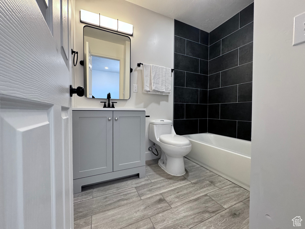 Full bath featuring toilet, vanity, shower / bath combination, and wood finished floors