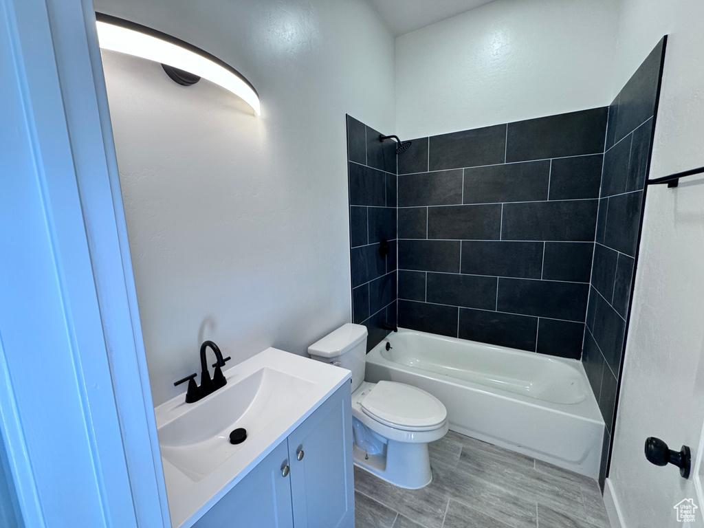 Bathroom featuring toilet,  shower combination, vanity, and wood finished floors