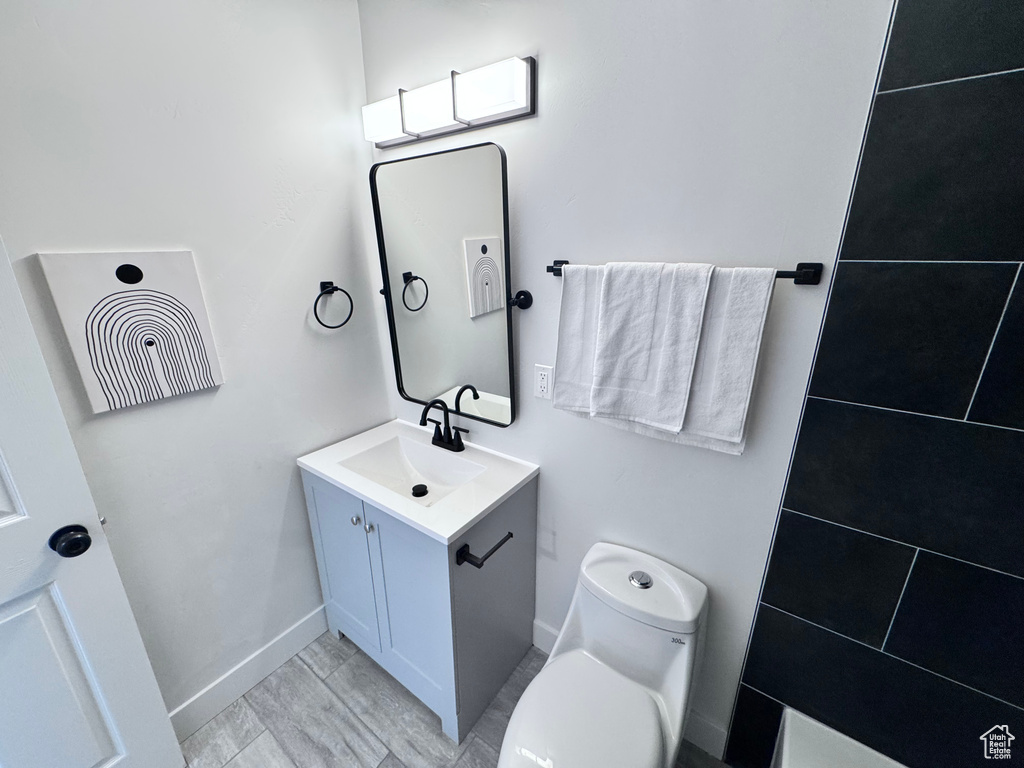 Bathroom featuring vanity, toilet, and baseboards