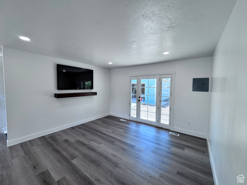 Unfurnished living room featuring electric panel, dark wood-style flooring, baseboards, recessed lighting, and a textured ceiling