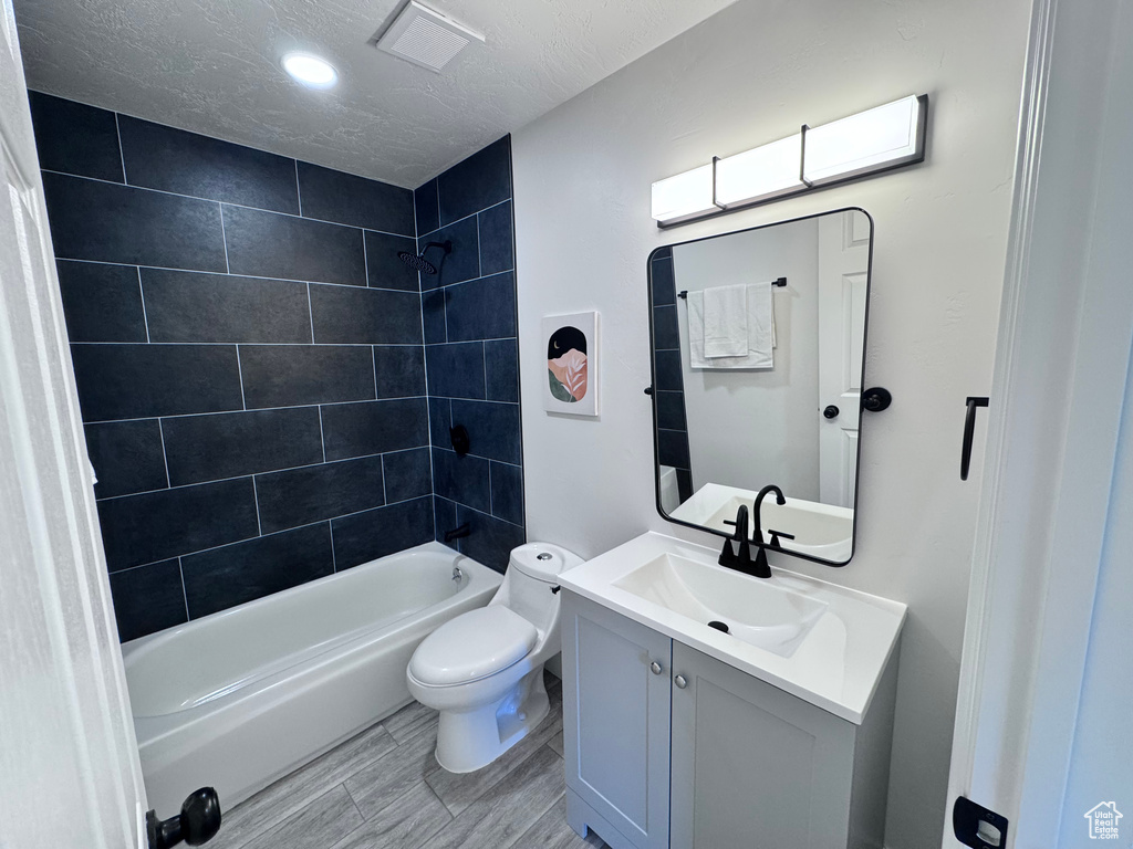Full bath featuring toilet, vanity, tub / shower combination, a textured ceiling, and recessed lighting