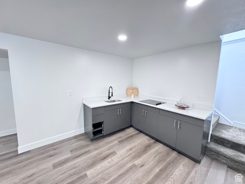 Kitchen with a sink, gray cabinets, light wood finished floors, and light countertops