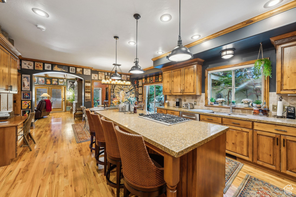 Kitchen with a sink, appliances with stainless steel finishes, tasteful backsplash, crown molding, and a center island