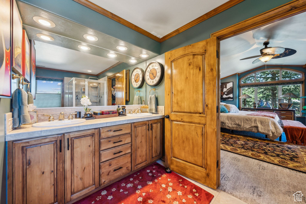 Ensuite bathroom with double vanity, a stall shower, ornamental molding, ceiling fan, and vaulted ceiling