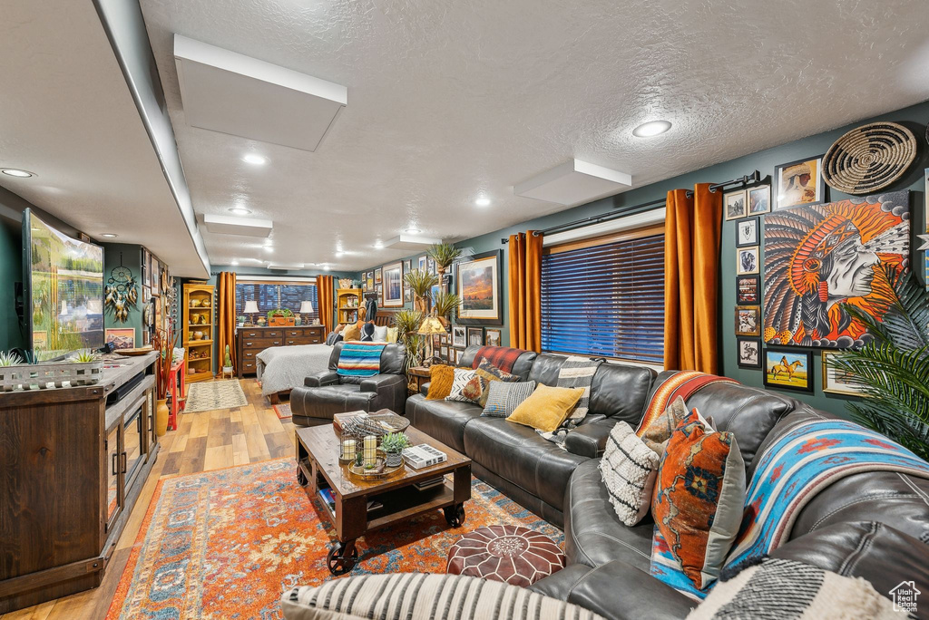 Living room with light wood finished floors, recessed lighting, and a textured ceiling