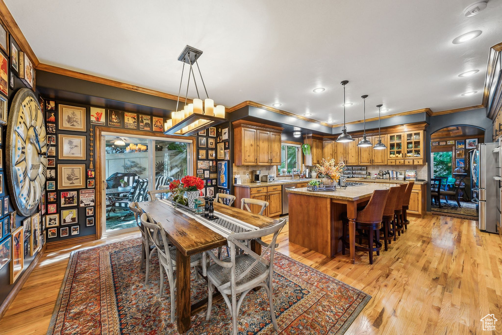 Dining area featuring crown molding, light wood finished floors, arched walkways, and recessed lighting