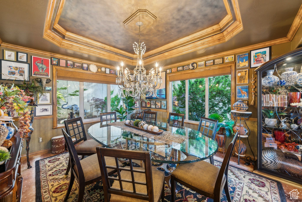 Dining area featuring a raised ceiling, healthy amount of natural light, a chandelier, and crown molding