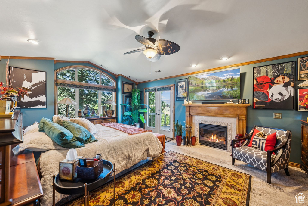 Carpeted bedroom featuring vaulted ceiling, crown molding, and a fireplace