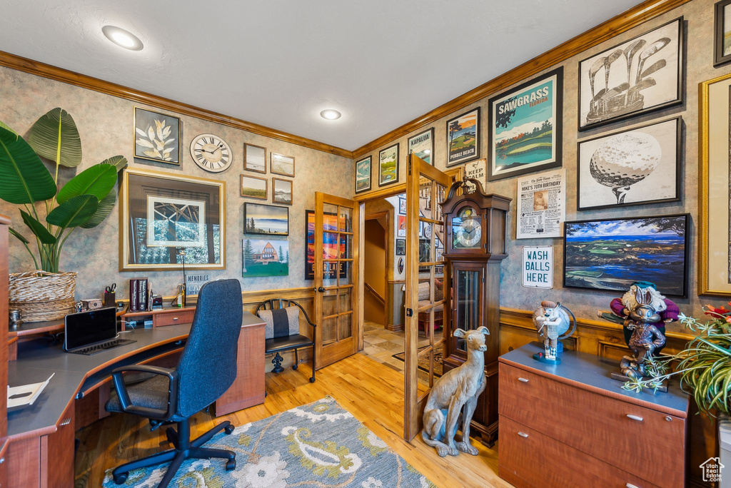 Home office featuring crown molding, wallpapered walls, wood finished floors, and a wainscoted wall
