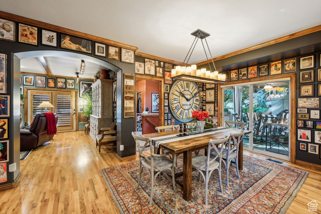 Dining area featuring arched walkways, wood finished floors, and crown molding