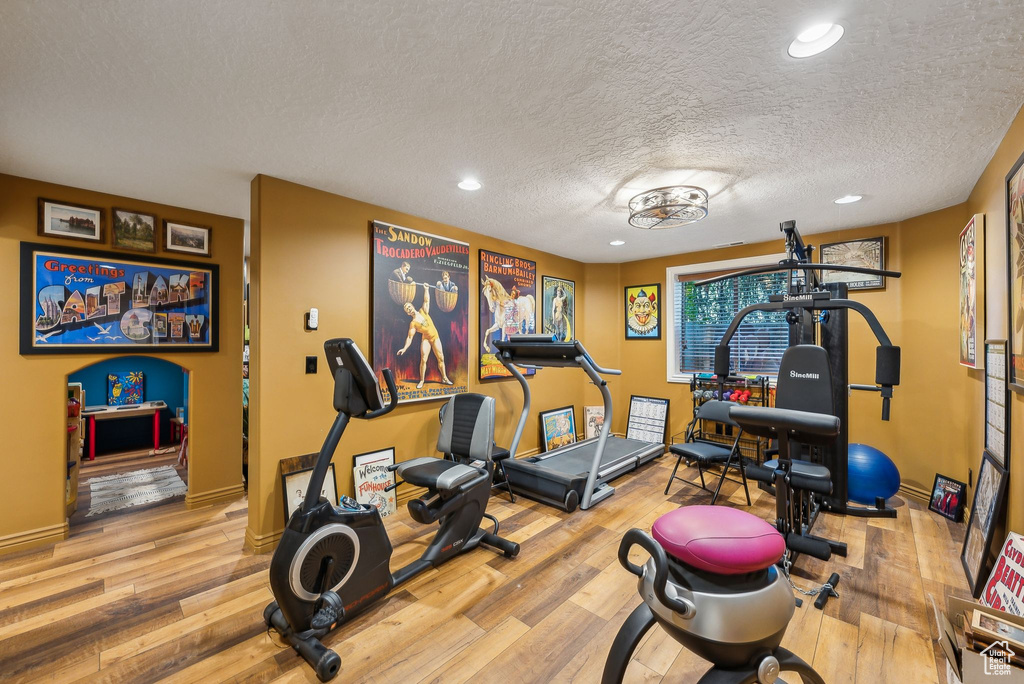 Workout area featuring wood finished floors, a textured ceiling, baseboards, and recessed lighting